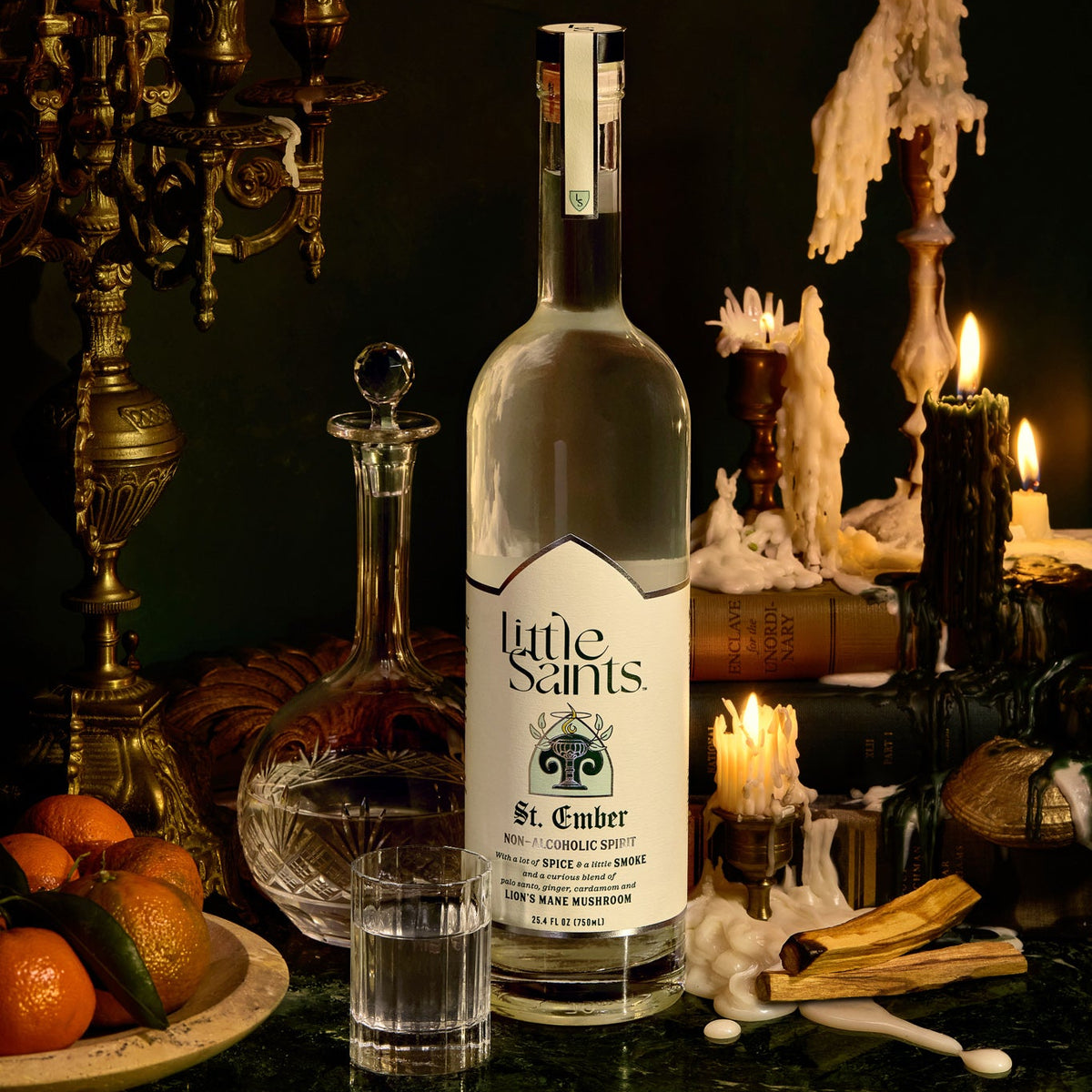 Bottle of Little Saints St. Ember liqueur on a dark table with candles and fruit